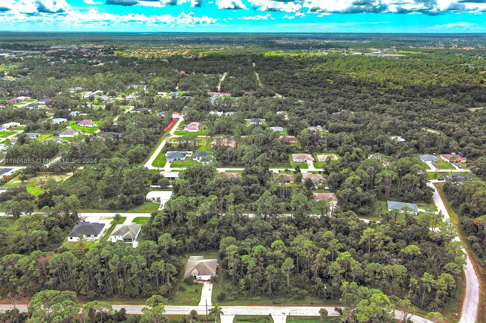 An aerial view shows houses scattered throughout a dense, wooded residential area under a cloudy sky — #1 Shaffer Ave, North Port FL 34291, NORTH PORT, FL