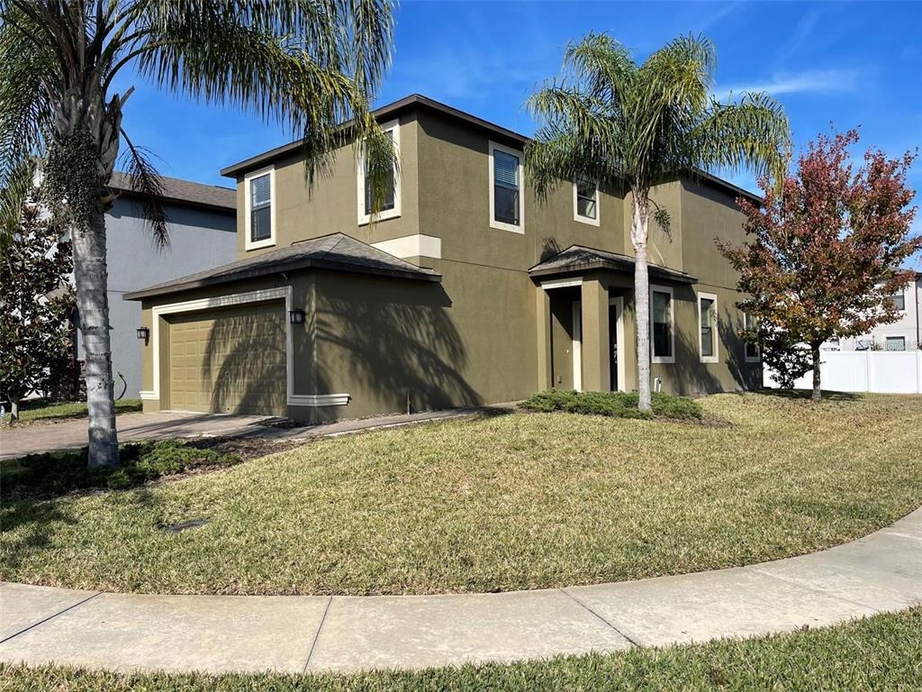 A two-story olive-colored house with a garage, palm trees, and a front lawn — 11796 CRESTRIDGE LOOP, NEW PORT RICHEY, FL