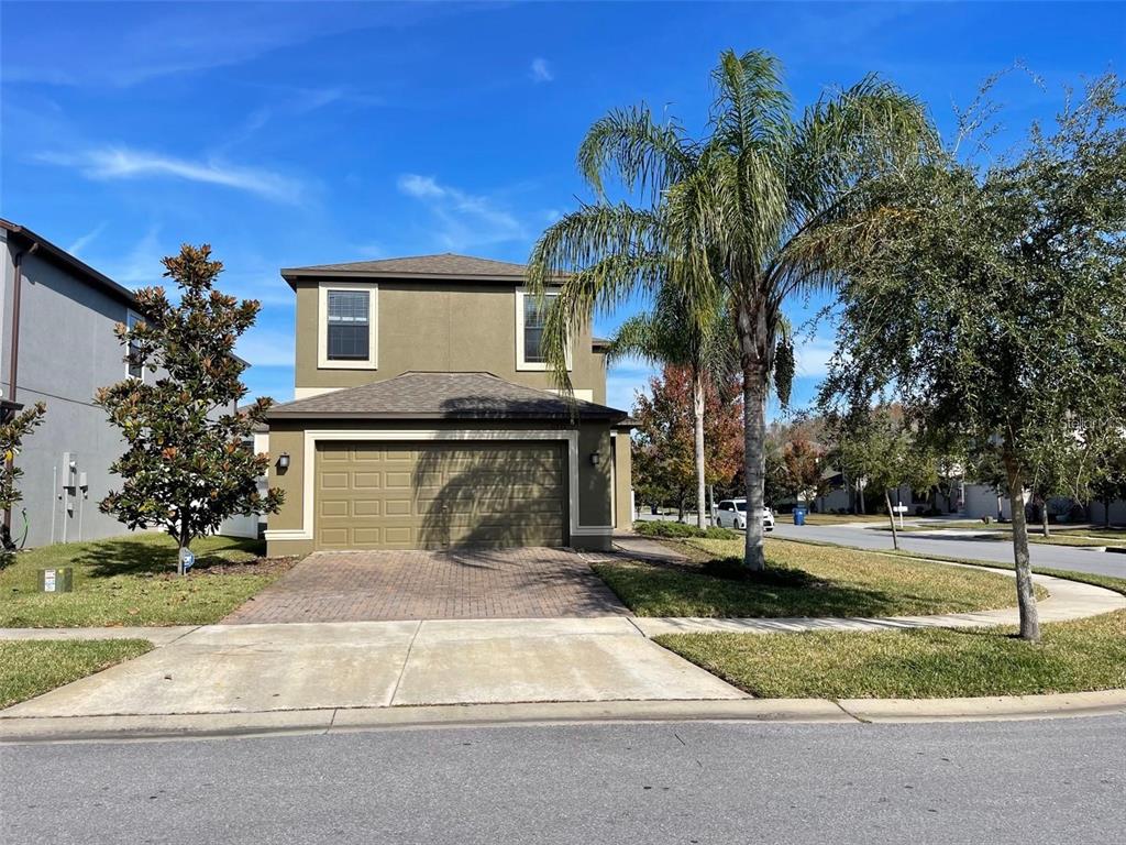 A two-story house with a tan stucco exterior, a two-car garage, and a palm tree — 11796 CRESTRIDGE LOOP, NEW PORT RICHEY, FL