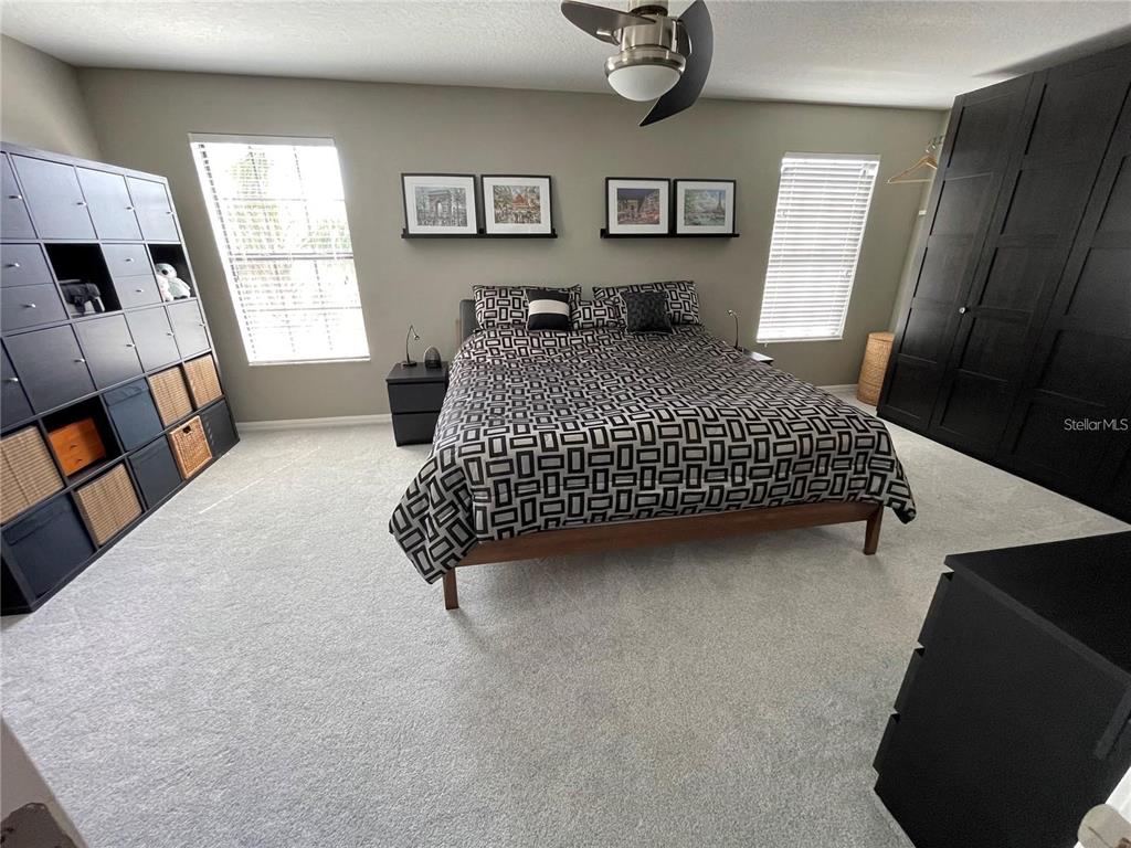 A bedroom features a bed with a geometric patterned comforter, black storage units, and carpet — 11796 CRESTRIDGE LOOP, NEW PORT RICHEY, FL