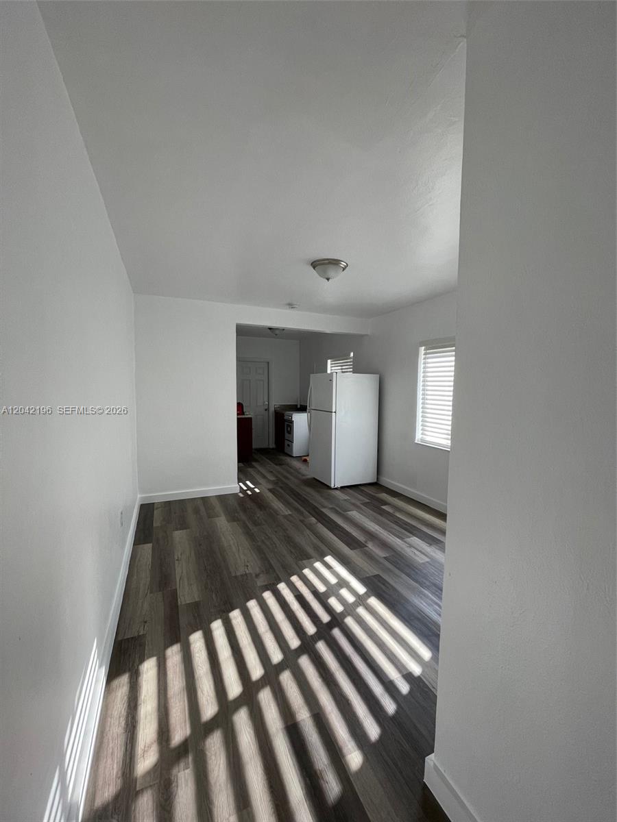 A room with wood-look flooring leads to a kitchen area featuring a white refrigerator — 430 SW 6th Ave # 8, Miami FL 33130, MIAMI, FL
