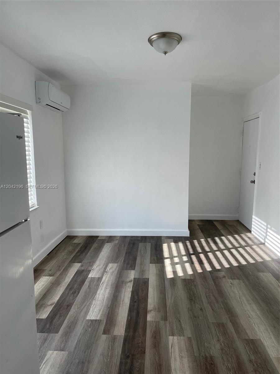 This room features white walls, wood-look flooring, a window, and a wall-mounted air conditioner — 430 SW 6th Ave # 8, Miami FL 33130, MIAMI, FL