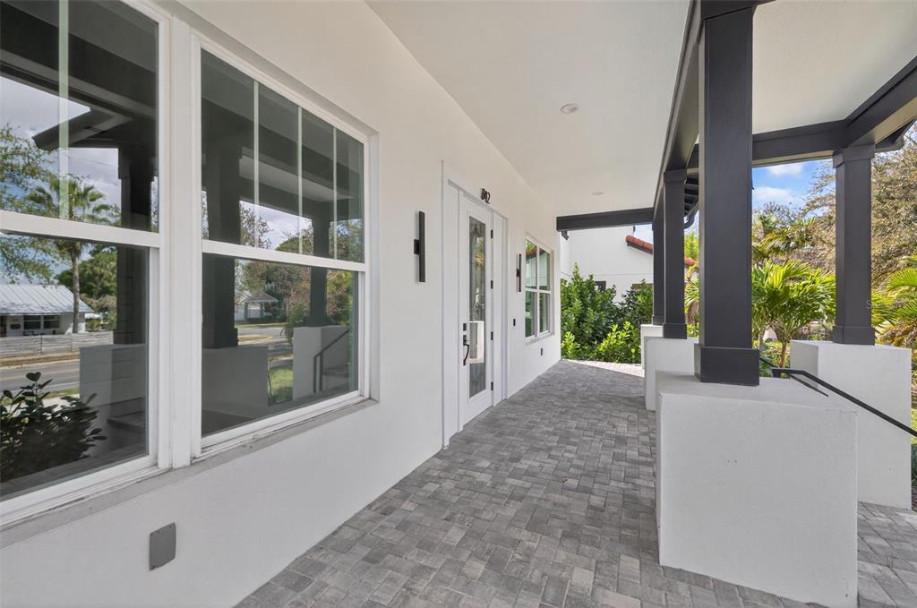 A covered front porch features gray paver flooring, white walls, and dark support columns — 842 30TH AVENUE, ST PETERSBURG, FL