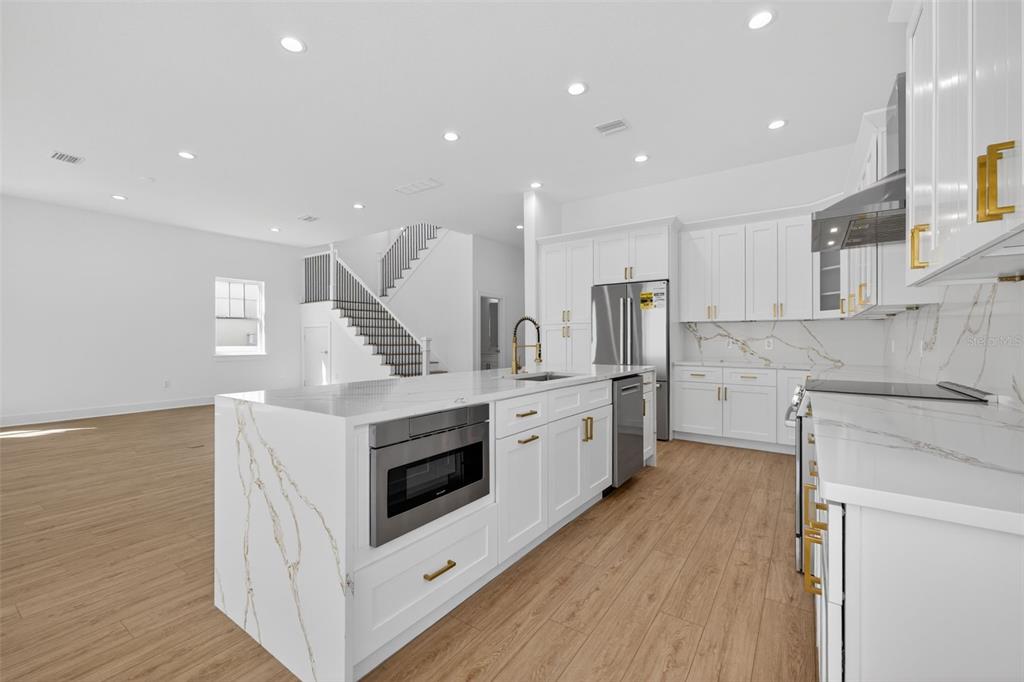 A modern kitchen features white cabinetry, a marble-topped island with a microwave, and wood flooring — 842 30TH AVENUE, ST PETERSBURG, FL