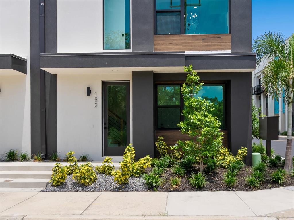 The exterior of a modern two-story townhouse features white and dark gray walls with wood accents — 152 AUDUBON PLACE, SARASOTA, FL