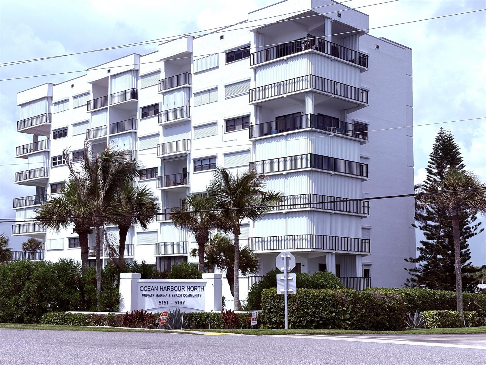 A multi-story white apartment building features balconies with black railings and surrounding palm trees — 5151 N Highway A1a # 513, Fort Pierce FL 34949, FORT PIERCE, FL