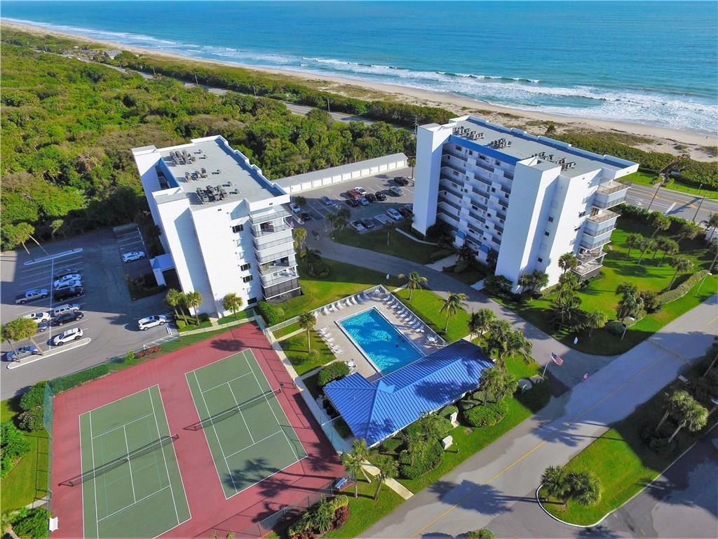 An aerial view shows two residential buildings, a swimming pool, and tennis courts near the ocean — 5151 N Highway A1a # 513, Fort Pierce FL 34949, FORT PIERCE, FL