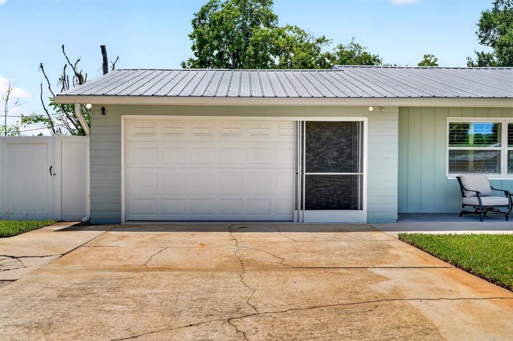 A light green house exterior features a white garage door, a screen door, and driveway — 2334 CITRUS AVENUE, SOUTH DAYTONA, FL