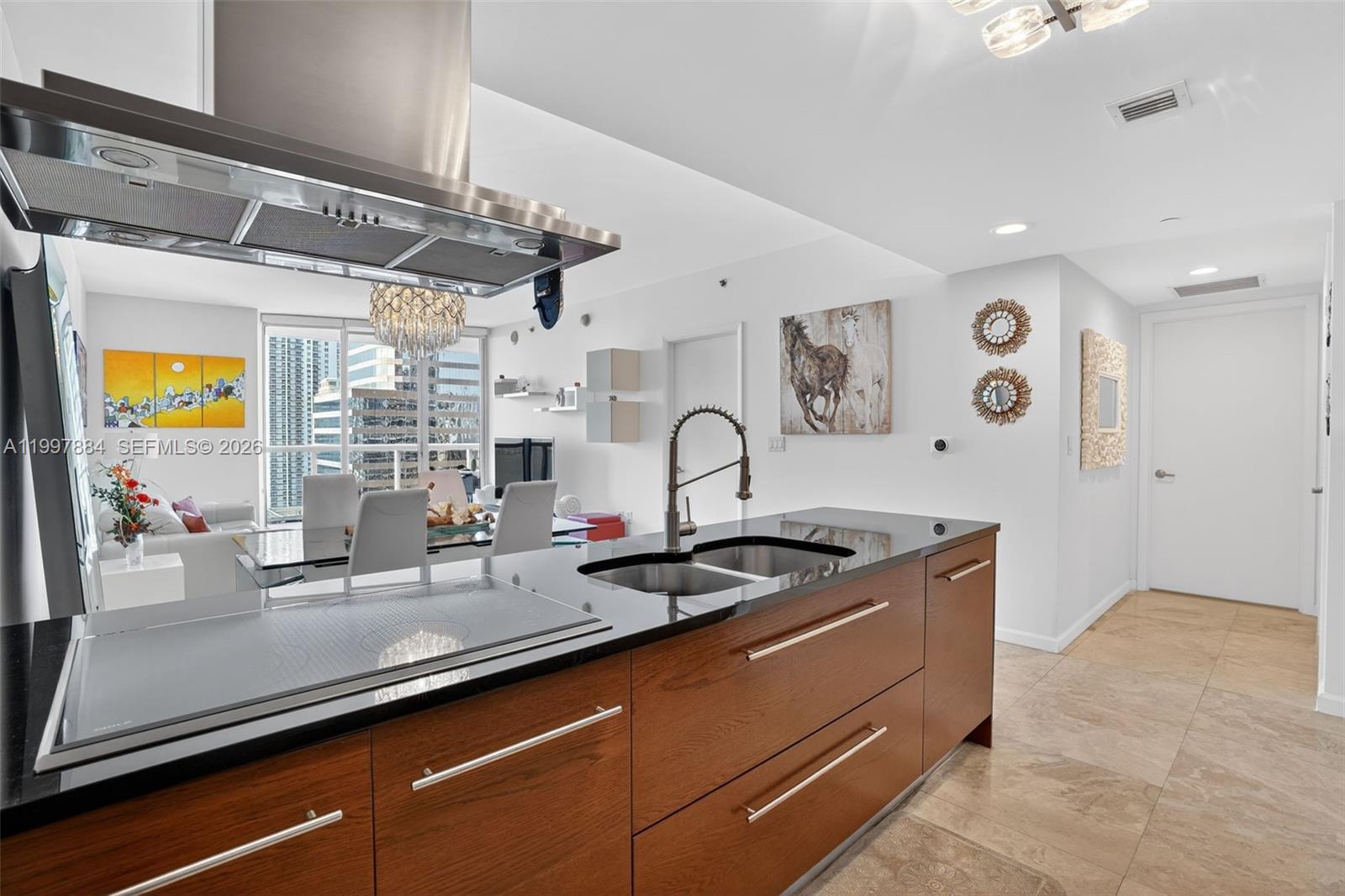 A modern kitchen features dark wood cabinetry, black countertops, and a stainless steel range hood — 495 Brickell Ave # 2807, Miami FL 33131, MIAMI, FL