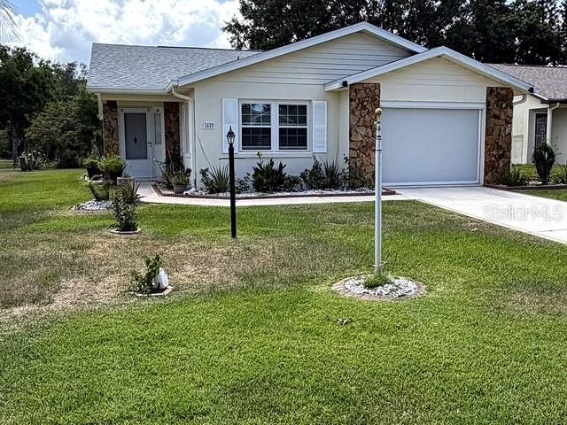 A single-story house with light siding, stone accents, and a two-car garage — 1629 WILLOW RUN, SEBRING, FL