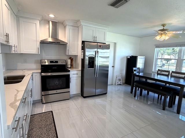 A modern kitchen features white cabinetry, stainless steel appliances, and a dining area with tile floors — 1629 WILLOW RUN, SEBRING, FL