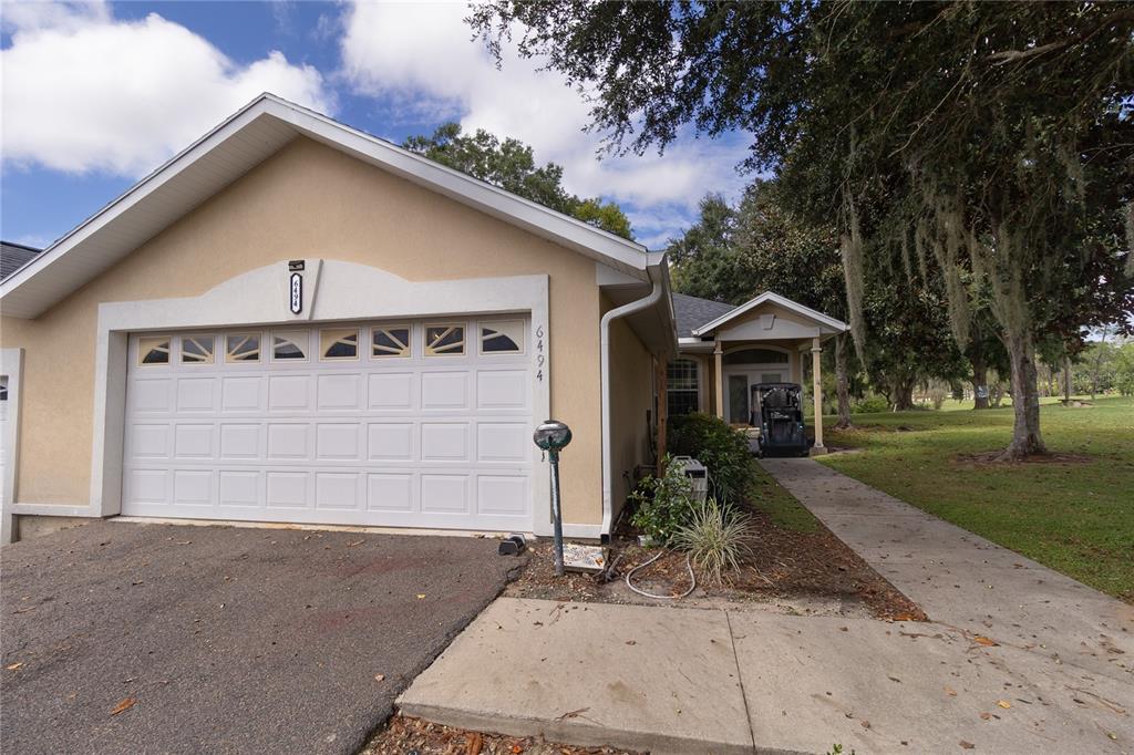 A beige house with a white garage door and a walkway leading to the entrance — 6494 NW 109TH PLACE, ALACHUA, FL
