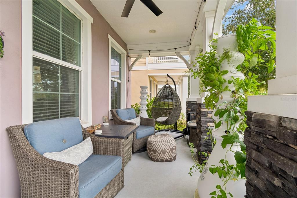 A covered porch features wicker chairs, a hanging egg chair, and a vertical hydroponic garden — 3441 BUMELIA LANE, NEW PORT RICHEY, FL