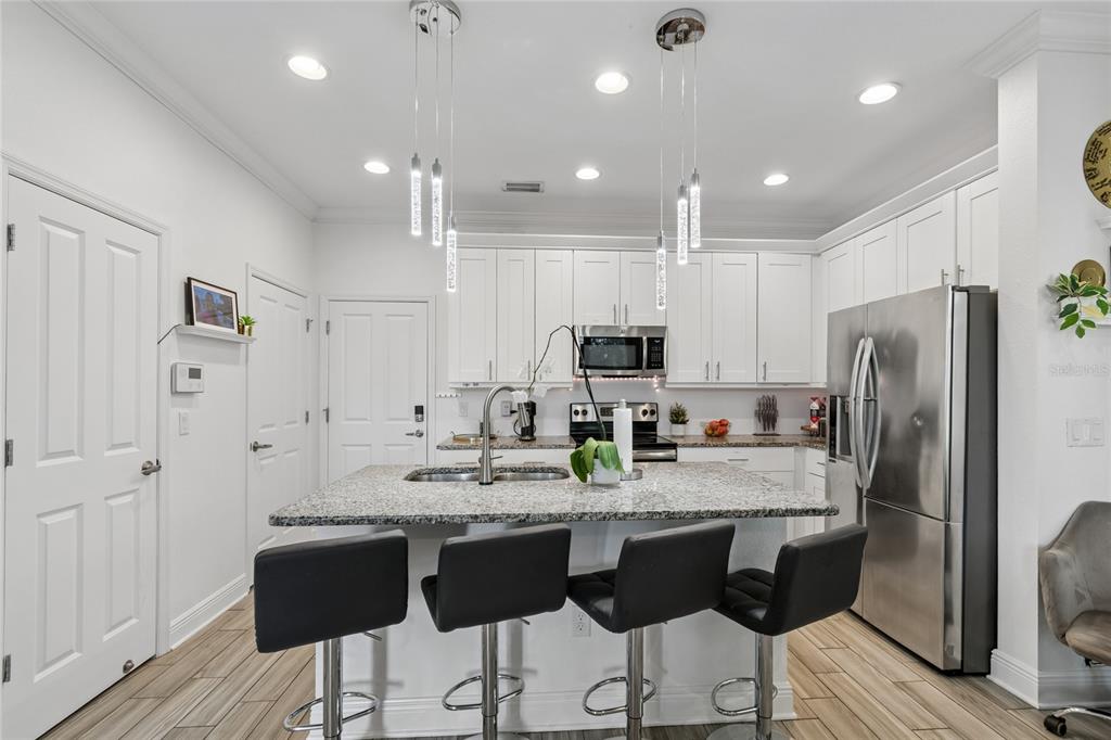 A kitchen with white cabinets, granite countertops, a center island, and four black bar stools — 3441 BUMELIA LANE, NEW PORT RICHEY, FL