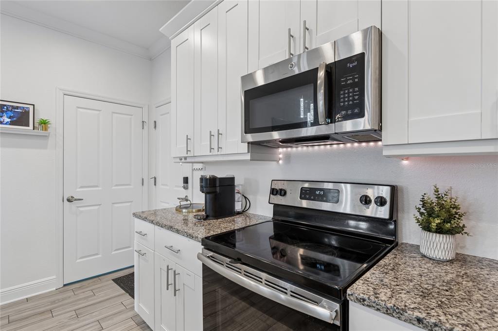 A kitchen features white cabinets, granite countertops, and stainless steel appliances including a microwave and stove — 3441 BUMELIA LANE, NEW PORT RICHEY, FL