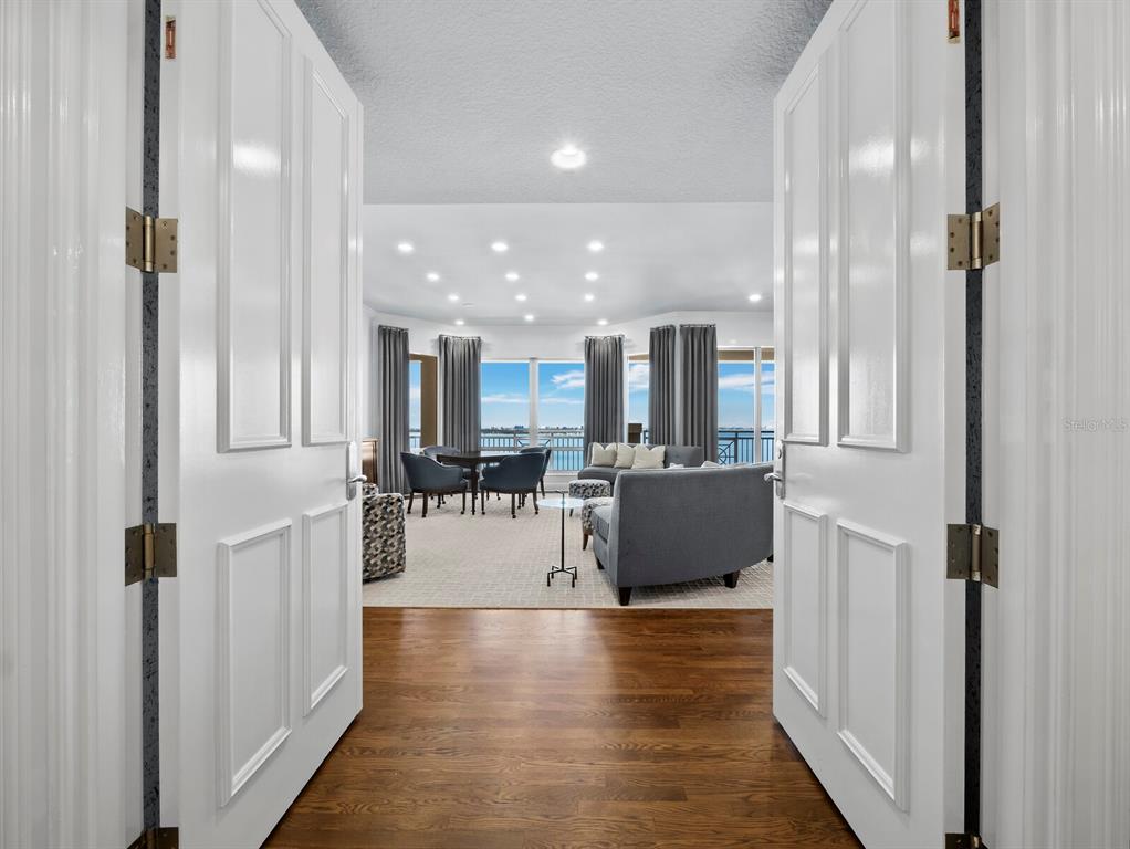 A view through double doors into a living room with hardwood floors and waterfront views — 35 WATERGATE DRIVE UNIT 1403, SARASOTA, FL