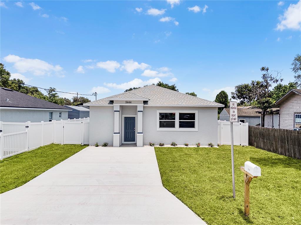 A single-story house with a light gray exterior, a concrete driveway, and a white fence — 5444 SIMMONS RD, LAKELAND, FL