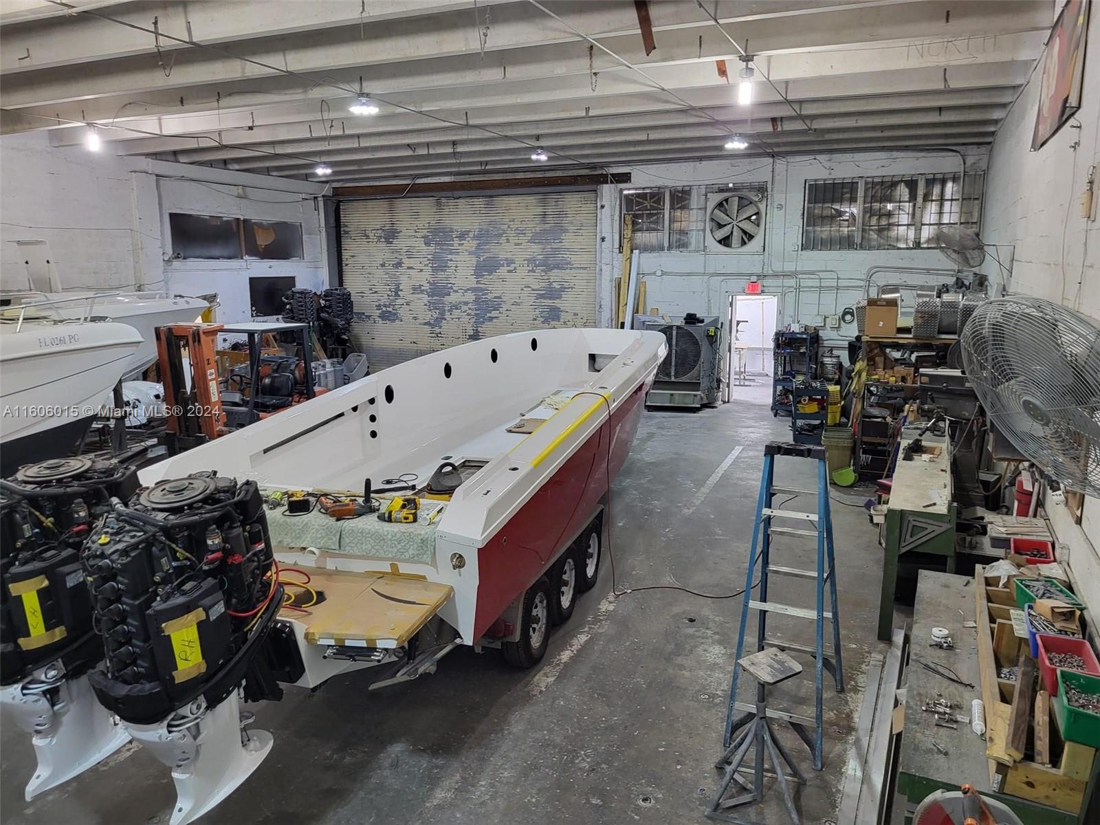 A boat under repair sits on a trailer inside a large industrial workshop space — 2157 NW 23rd Ave, Miami FL 33142, MIAMI, FL
