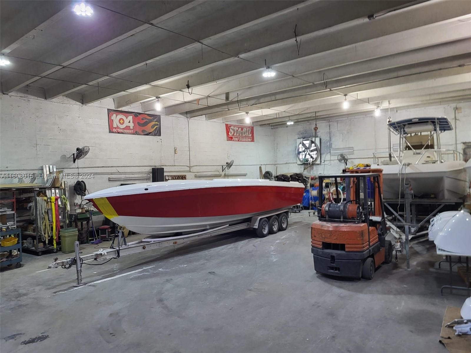 A large indoor warehouse space contains a red and white boat on a trailer and a forklift — 2157 NW 23rd Ave, Miami FL 33142, MIAMI, FL