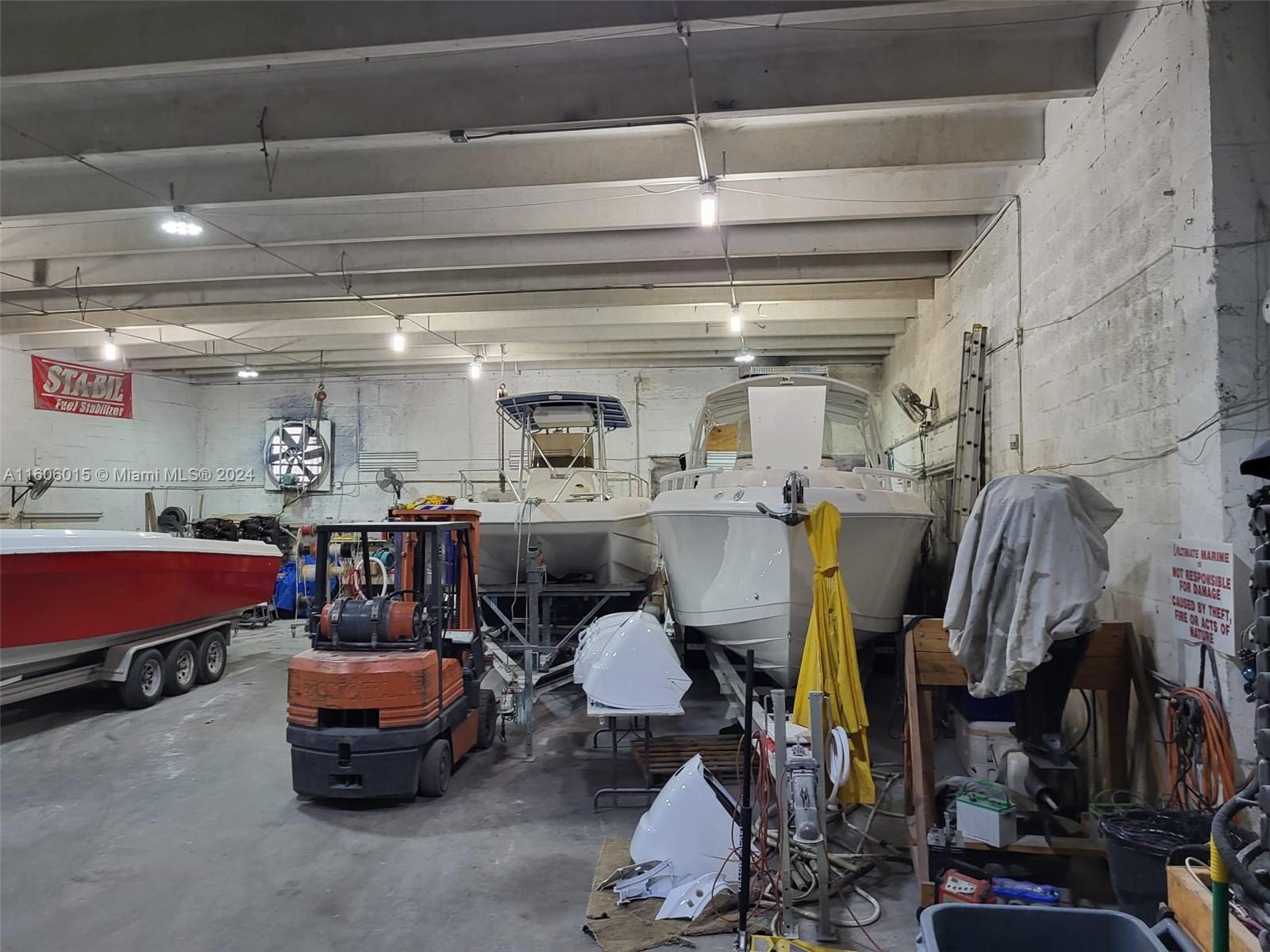 A large industrial warehouse space contains several boats on trailers and a parked orange forklift — 2157 NW 23rd Ave, Miami FL 33142, MIAMI, FL