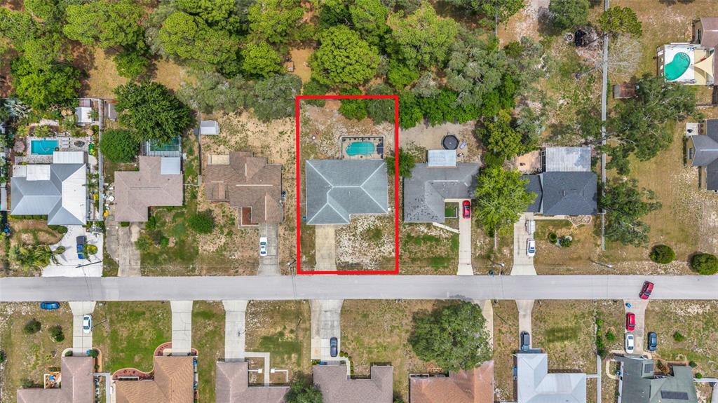 This aerial view shows a single-family home with a backyard pool and driveway — 1372 HAULOVER AVENUE, SPRING HILL, FL