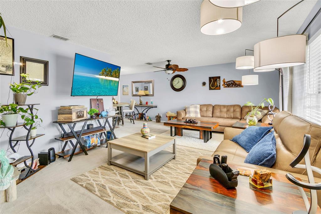 A living room features a large sectional sofa, a television, and multiple coffee tables — 1372 HAULOVER AVENUE, SPRING HILL, FL