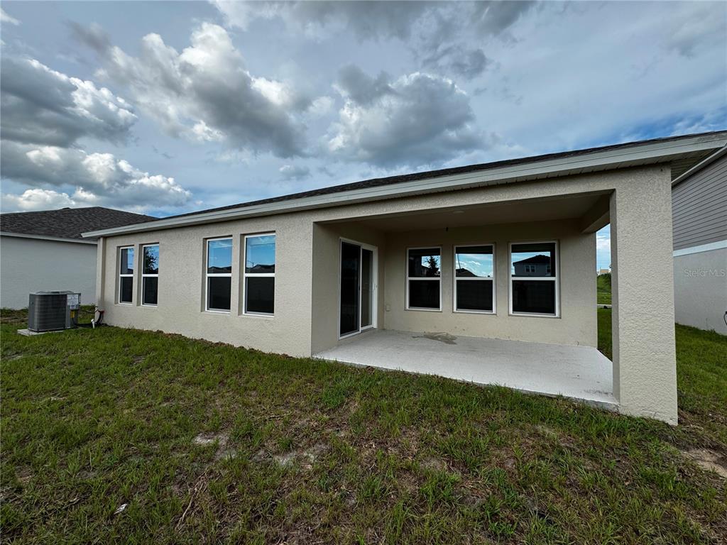 The exterior view shows a house with a covered concrete patio and a grassy yard — 1338 PALMEROY ROAD, HAINES CITY, FL
