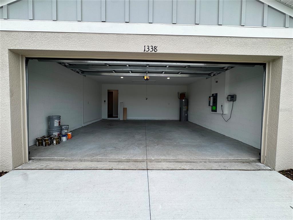 An open garage features a concrete floor, white block walls, and an electric vehicle charger — 1338 PALMEROY ROAD, HAINES CITY, FL