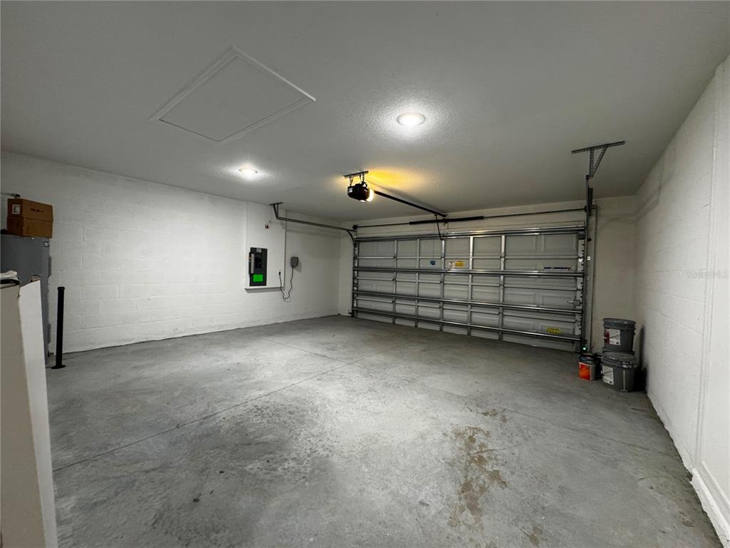 An empty garage with white concrete block walls, a concrete floor, and a metal door — 1338 PALMEROY ROAD, HAINES CITY, FL