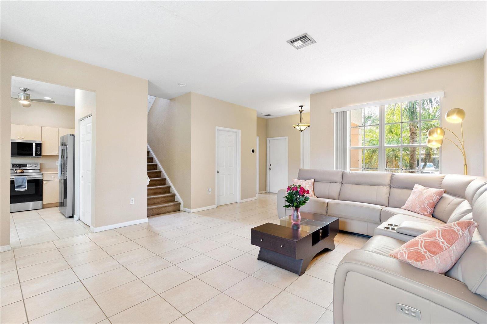 A living room with light tile floors, a sectional sofa, and an adjacent open kitchen — 16385 SW 27th Street, Miramar FL 33027, MIRAMAR, FL