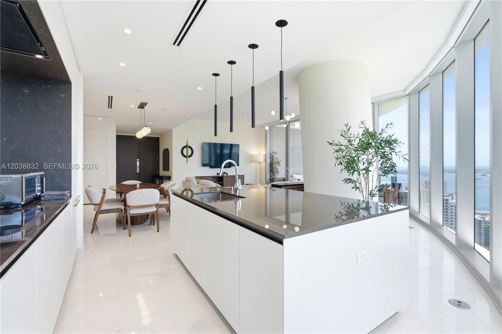 A modern kitchen features a large white island with a dark countertop and floor-to-ceiling windows — 300 Biscayne Boulevard Way # 4007W, Miami FL 33131, MIAMI, FL