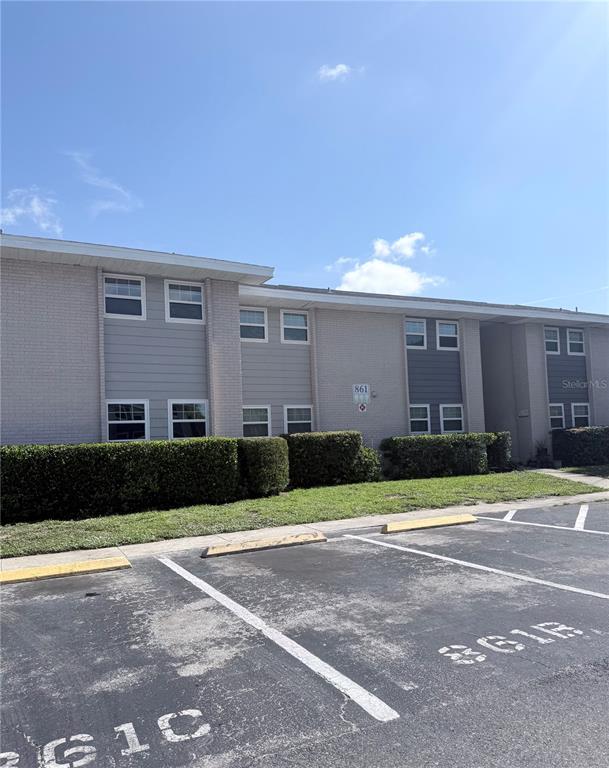 A two-story apartment building with light-colored brick, gray siding, and a parking lot in front — 861 SKY LAKE CIRCLE UNIT C, ORLANDO, FL