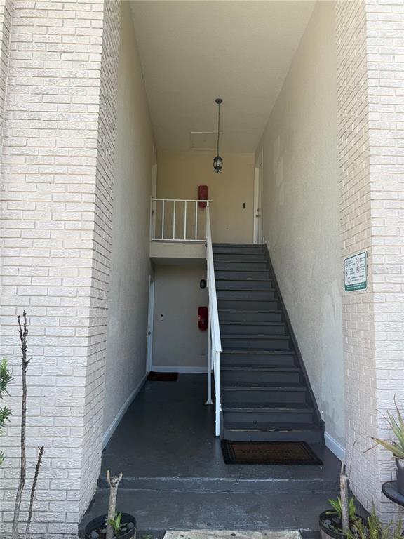 An outdoor stairwell with dark painted steps leads to an upper-level landing between brick walls — 861 SKY LAKE CIRCLE UNIT C, ORLANDO, FL