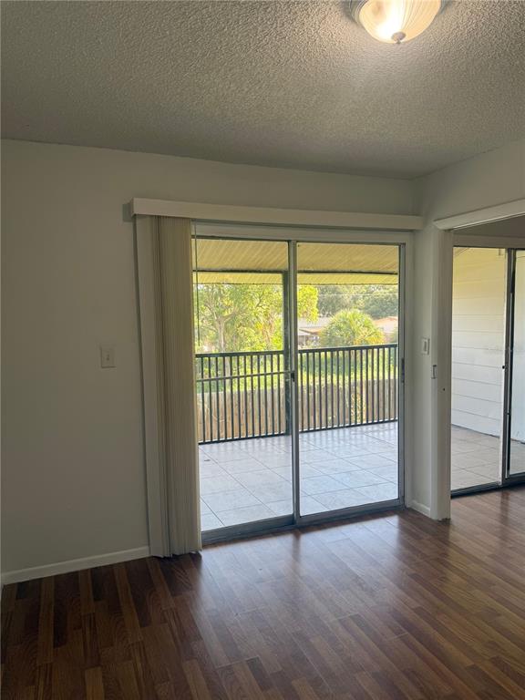 An interior room with wood-look flooring and sliding glass doors leading to a covered balcony — 861 SKY LAKE CIRCLE UNIT C, ORLANDO, FL