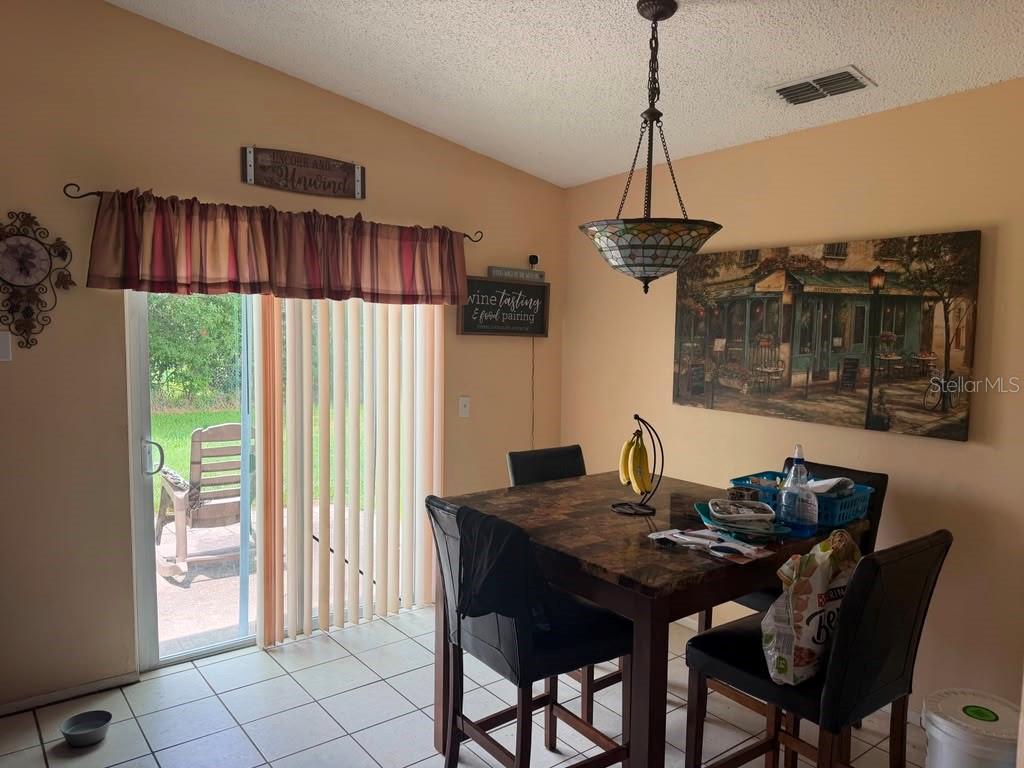 A dining area features a tile floor, a dark wood table, and a sliding glass door — 2114 WIND JAMMER COURT, KISSIMMEE, FL