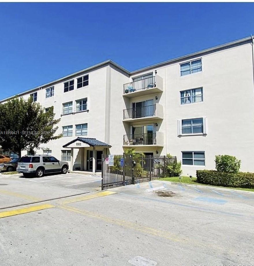 A multi-story apartment building with a gated entrance and a parking lot in front — 5501 NW 7th St # E219, Miami FL 33126, MIAMI, FL