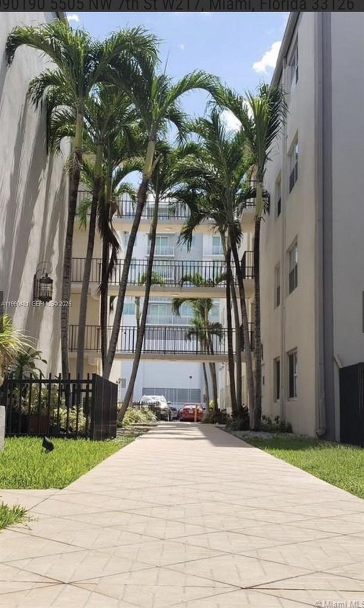 A paved walkway leads between two apartment buildings connected by elevated outdoor pedestrian bridges — 5501 NW 7th St # E219, Miami FL 33126, MIAMI, FL