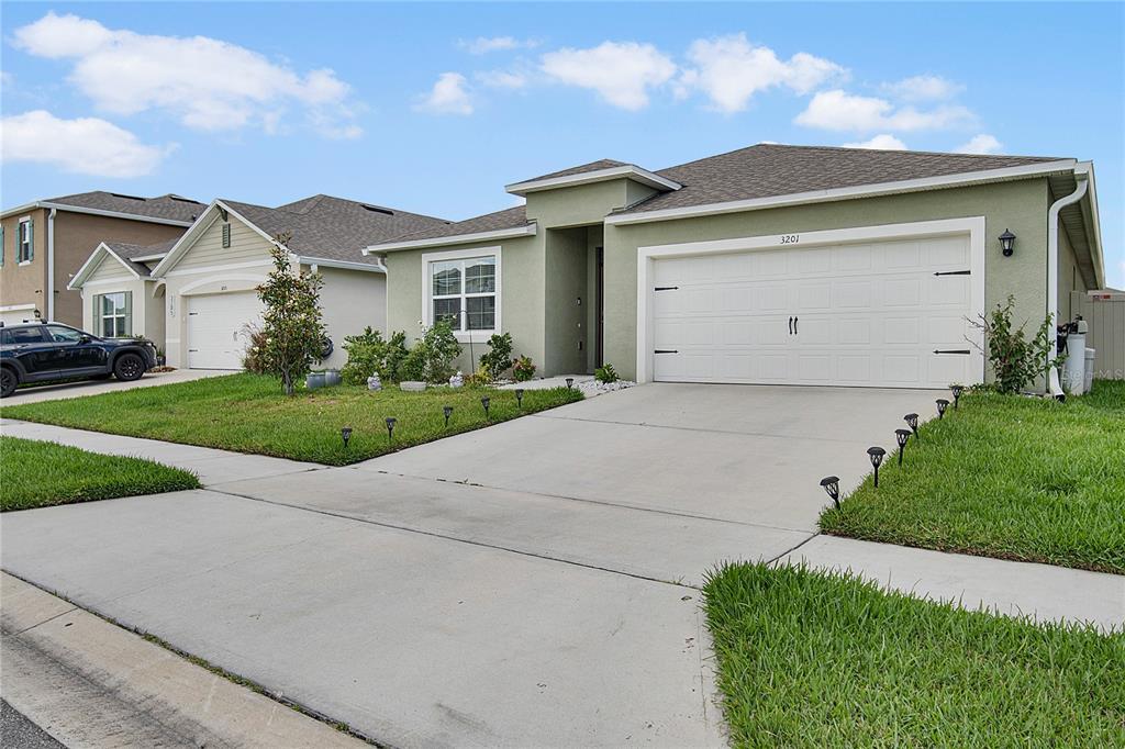 A light green single-story house with a two-car garage and a concrete driveway — 3201 EASTGROVE TERRACE, SANFORD, FL
