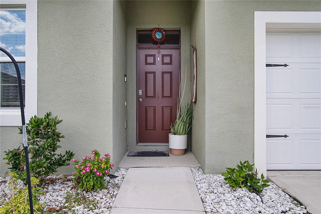 A front entryway features a dark brown door, a concrete walkway, and light-colored stucco walls — 3201 EASTGROVE TERRACE, SANFORD, FL