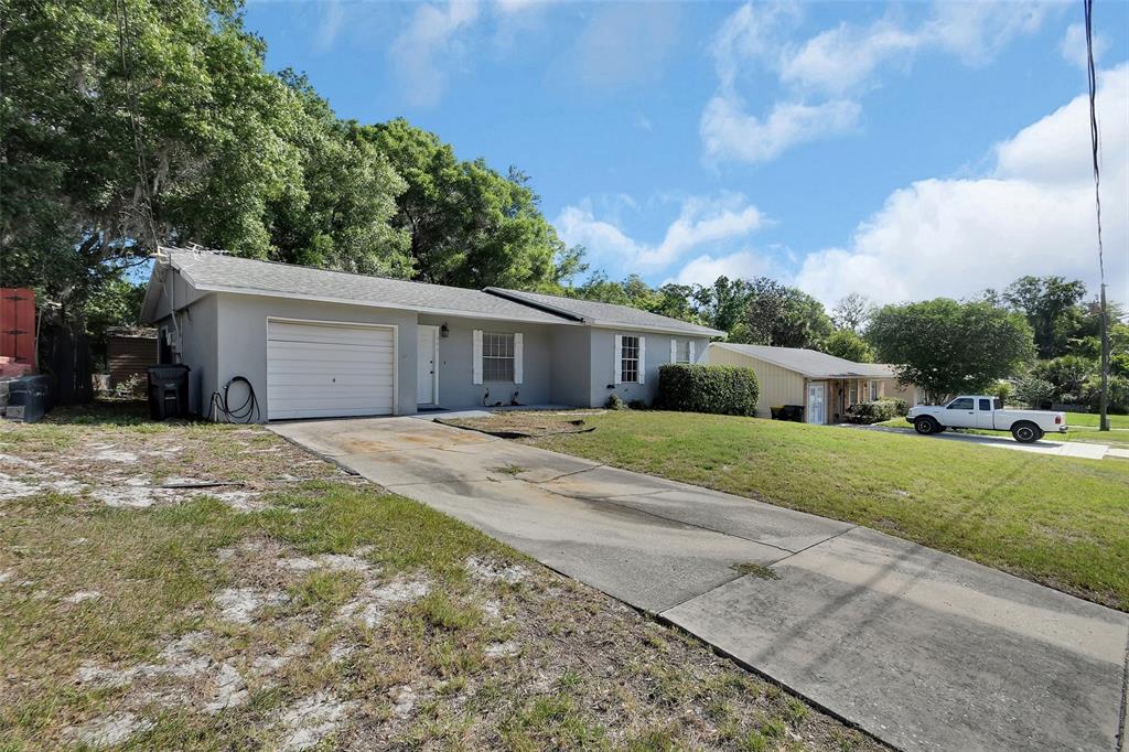 A single-story gray house with a one-car garage and a concrete driveway — 555 SANDY PINES DRIVE, ORANGE CITY, FL