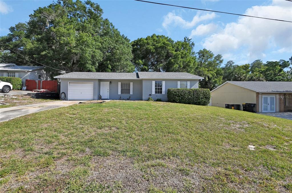 A single-story gray house with a garage and a large front lawn — 555 SANDY PINES DRIVE, ORANGE CITY, FL