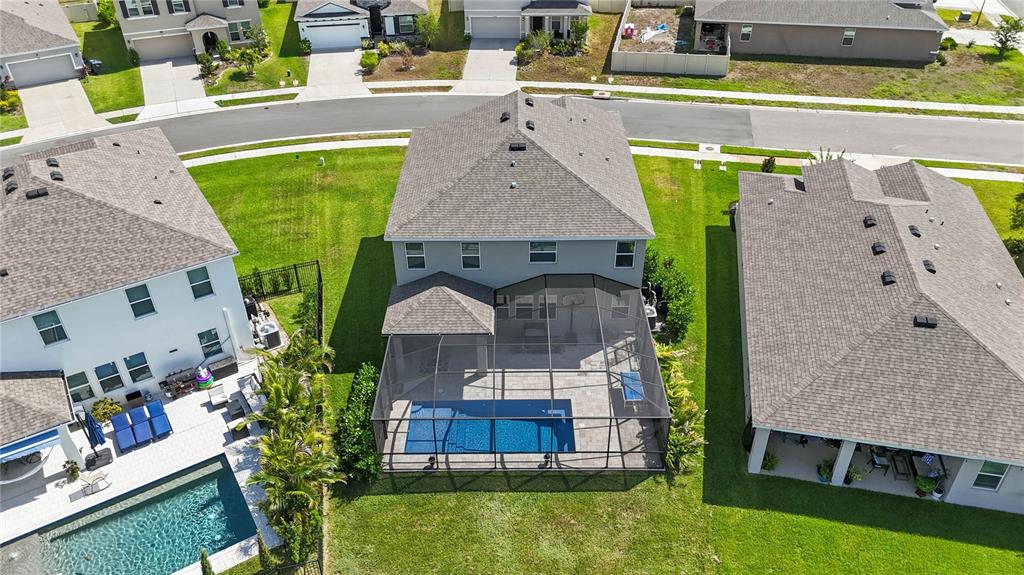 An aerial view shows a two-story house with a screened-in pool and patio area — 3830 LIVELY CORAL PLACE, BRADENTON, FL