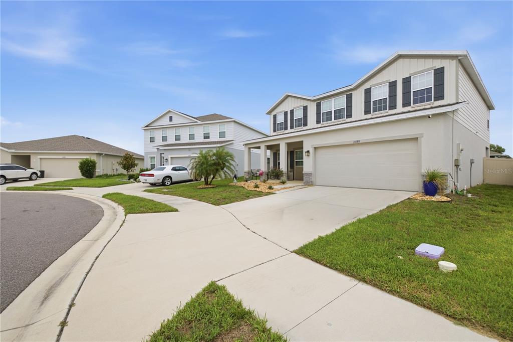 A two-story suburban house with a beige exterior, a two-car garage, and a concrete driveway — 10188 AGAVE COURT, LAND O LAKES, FL