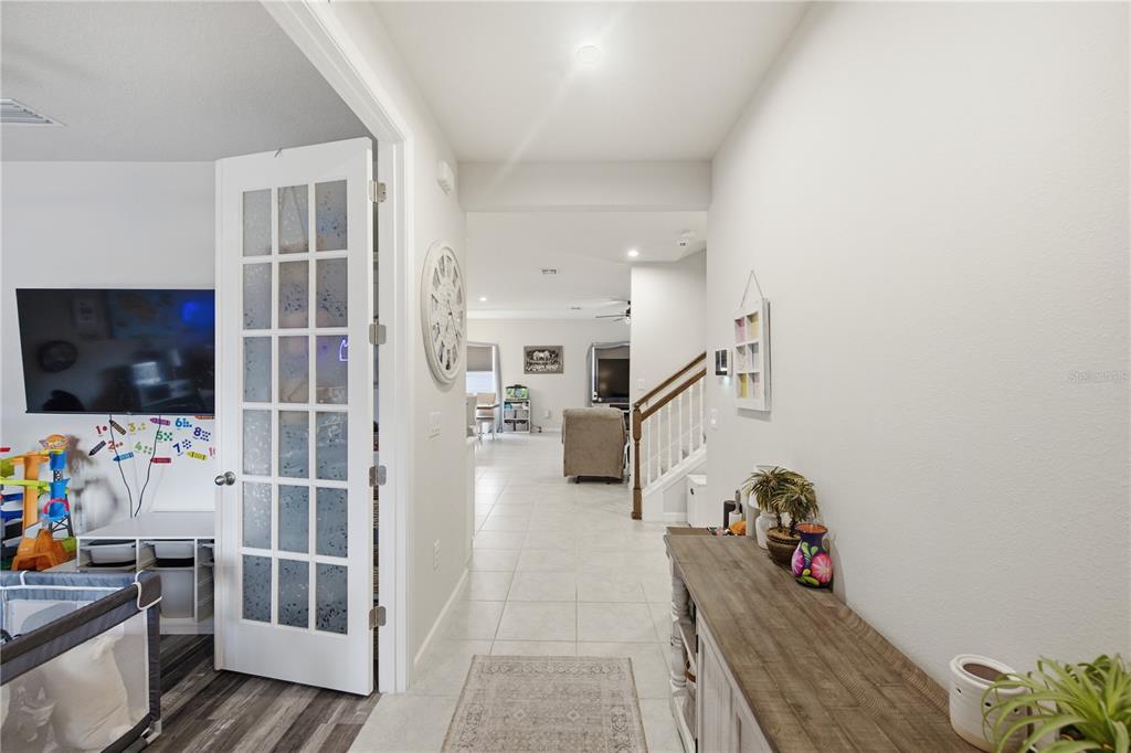 A view from a hallway looking into a living area with tile floors and stairs — 10188 AGAVE COURT, LAND O LAKES, FL