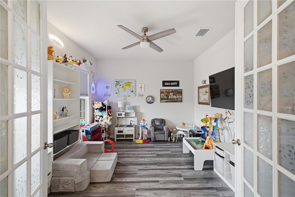 A playroom with wood-look flooring, a ceiling fan, a wall-mounted television, and various toys — 10188 AGAVE COURT, LAND O LAKES, FL