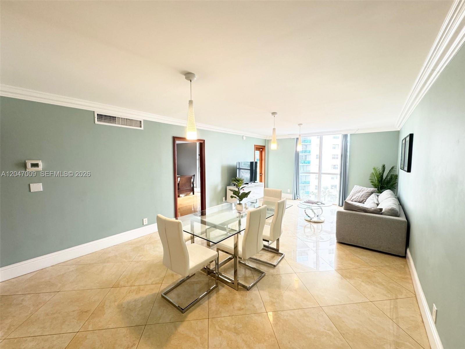 A dining and living area features light green walls, tile flooring, and floor-to-ceiling windows — 3901 S Ocean Dr # 7O, Hollywood FL 33019, HOLLYWOOD, FL