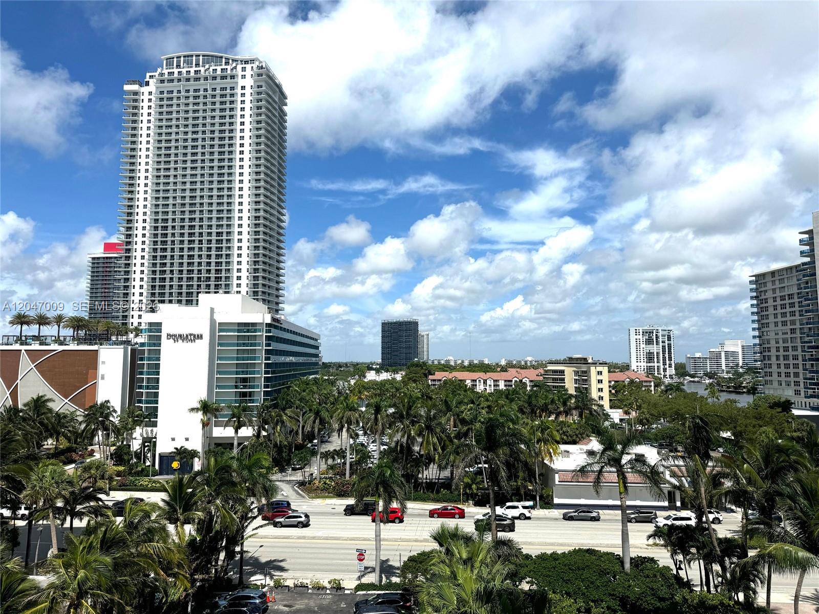 An elevated view shows a tall skyscraper, a DoubleTree hotel, and palm trees along a road — 3901 S Ocean Dr # 7O, Hollywood FL 33019, HOLLYWOOD, FL