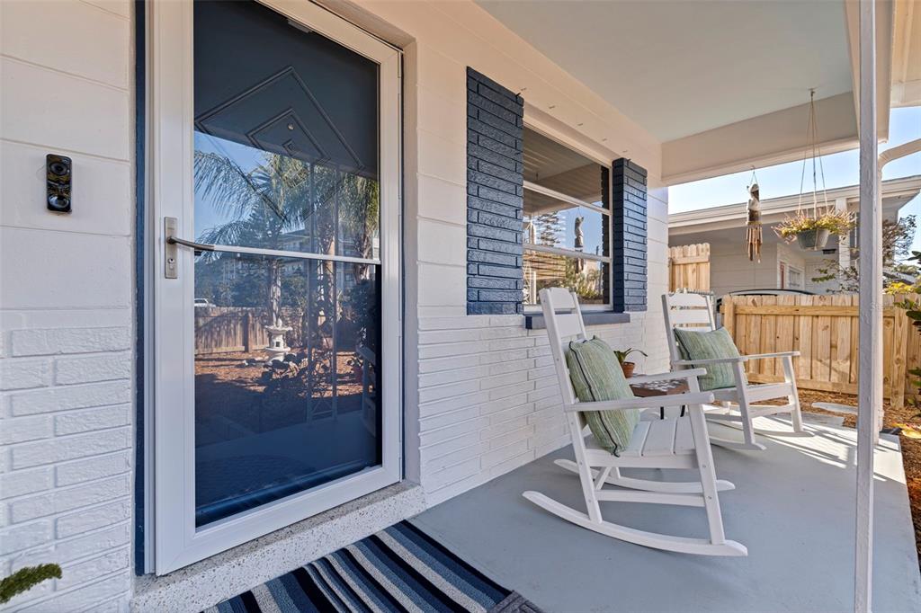 A covered front porch features white brick walls, two white rocking chairs, and a storm door — 3038 58TH STREET S, GULFPORT, FL