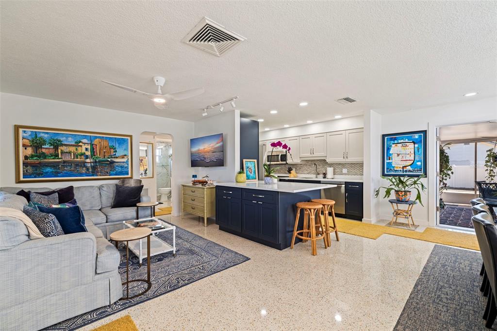 An open-concept living room and kitchen featuring a blue island, white cabinets, and terrazzo flooring — 3038 58TH STREET S, GULFPORT, FL