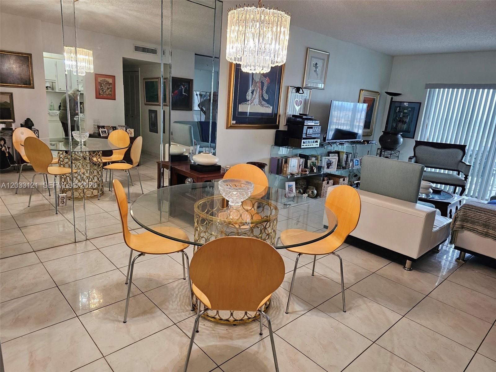 A dining area with a glass table and light wood chairs sits before a living room — 3850 Washington St # 1011, Hollywood FL 33021, HOLLYWOOD, FL